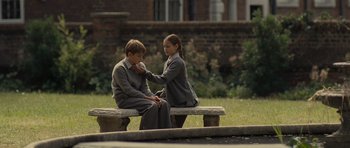 Movie still from “Never Let Me Go” (2010), directed by Mark Romanek – Two people sitting on top of a wooden bench; Medium shot, High angle