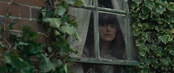 Movie still from “Never Let Me Go” (2010), directed by Mark Romanek – A woman looking out of a window through a lace curtain; Close Up shot, Over the shoulder angle