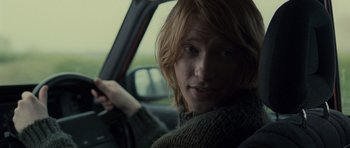 Movie still from “Never Let Me Go” (2010), directed by Mark Romanek – A person sitting in a car with a steering wheel; Close Up shot, Over the shoulder angle