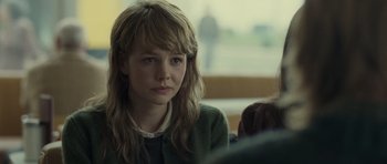 Movie still from “Never Let Me Go” (2010), directed by Mark Romanek – A young woman sitting in front of other people; Close Up shot, Over the shoulder angle