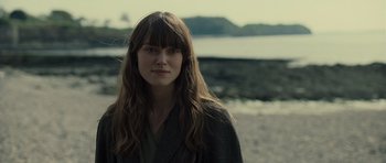 Movie still from “Never Let Me Go” (2010), directed by Mark Romanek – A woman with long brown hair standing on the beach; Close Up shot, Over the shoulder angle