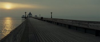 Movie still from “Never Let Me Go” (2010), directed by Mark Romanek – Two people are sitting on a bench on a pier; Extreme Wide shot, Low angle