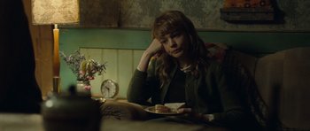 Movie still from “Never Let Me Go” (2010), directed by Mark Romanek – A woman sitting at a table with a piece of cake in front of her face; Medium shot, Over the shoulder angle