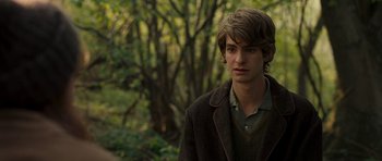 Movie still from “Never Let Me Go” (2010), directed by Mark Romanek – A young man in a brown jacket standing in front of trees; Close Up shot, Over the shoulder angle