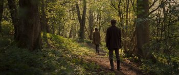 Movie still from “Never Let Me Go” (2010), directed by Mark Romanek – A man and a woman walking down a path in the woods; Wide shot, Over the shoulder angle