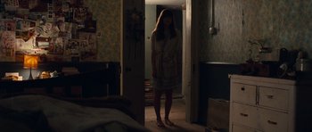 Movie still from “Never Let Me Go” (2010), directed by Mark Romanek – A woman standing in a doorway in a dark room; Wide shot, High angle