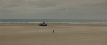 Movie still from “Never Let Me Go” (2010), directed by Mark Romanek – A person walking on the beach with a boat in the background; Extreme Wide shot, High angle