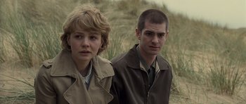 Movie still from “Never Let Me Go” (2010), directed by Mark Romanek – A man and a woman standing next to each other in a field; Medium shot, Over the shoulder angle