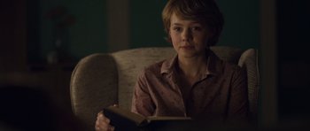Movie still from “Never Let Me Go” (2010), directed by Mark Romanek – A woman sitting in a chair reading a book; Close Up shot, Over the shoulder angle