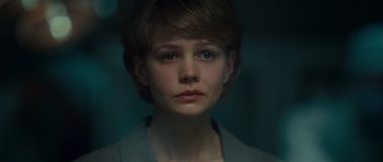 Movie still from “Never Let Me Go” (2010), directed by Mark Romanek – A woman with short blonde hair is looking at the camera; Close Up shot, Over the shoulder angle
