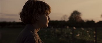 Movie still from “Never Let Me Go” (2010), directed by Mark Romanek – A young boy looking into the distance in a field; Close Up shot, Over the shoulder angle
