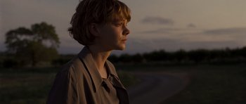 Movie still from “Never Let Me Go” (2010), directed by Mark Romanek – A woman with short blonde hair is standing in the dark; Close Up shot, Over the shoulder angle