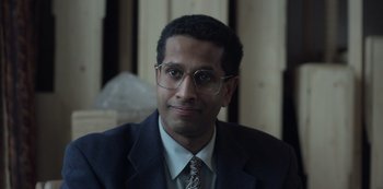Movie still from “The Crown” (2016), created by Peter Morgan – A person wearing glasses and a suit; Close Up shot, Low angle