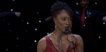 Movie still from “The Crown” (2016), created by Peter Morgan – A woman in a red dress is holding a microphone; Close Up shot, Over the shoulder angle