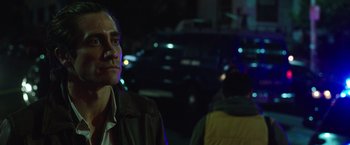 Movie still from “Nightcrawler” (2014), directed by Dan Gilroy – A man standing on a street at night with cars in the background; Close Up shot, Over the shoulder angle
