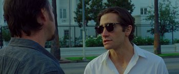 Movie still from “Nightcrawler” (2014), directed by Dan Gilroy – A man wearing sunglasses is talking to another man; Close Up shot, Over the shoulder angle