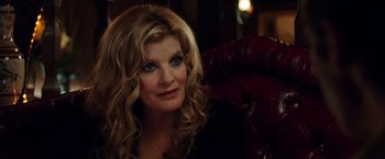 Movie still from “Nightcrawler” (2014), directed by Dan Gilroy – A woman sitting in a chair looking at the camera; Close Up shot, Over the shoulder angle