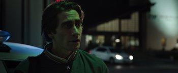 Movie still from “Nightcrawler” (2014), directed by Dan Gilroy – A man standing on a street at night with cars in the background; Close Up shot, Over the shoulder angle