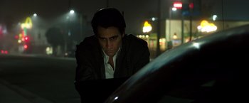 Movie still from “Nightcrawler” (2014), directed by Dan Gilroy – A man looking at a car in the dark at night; Close Up shot, Low angle