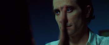 Movie still from “Nightcrawler” (2014), directed by Dan Gilroy – A person with his hand to his face; Close Up shot, Over the shoulder angle