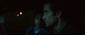 Movie still from “Nightcrawler” (2014), directed by Dan Gilroy – Two men are looking into the distance in the dark; Close Up shot, Over the shoulder angle