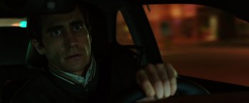 Movie still from “Nightcrawler” (2014), directed by Dan Gilroy – A man sitting in the drivers seat of a car at night; Close Up shot, Over the shoulder angle