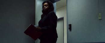 Movie still from “Nightcrawler” (2014), directed by Dan Gilroy – A woman in a black suit holding a red folder; Medium shot, Low angle