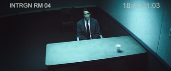 Movie still from “Nightcrawler” (2014), directed by Dan Gilroy – A man sitting at a table in front of a cup; Medium shot, High angle