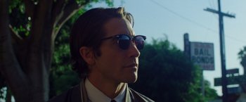 Movie still from “Nightcrawler” (2014), directed by Dan Gilroy – A person wearing a suit and sunglasses; Close Up shot, Low angle