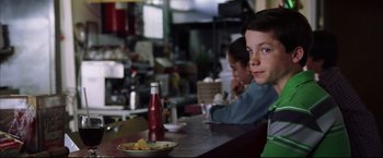 Movie still from “The Departed” (2006), directed by Martin Scorsese – A boy sitting at a table in front of a plate of food; Close Up shot, Over the shoulder angle