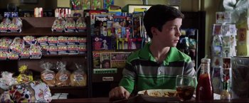 Movie still from “The Departed” (2006), directed by Martin Scorsese – A boy sitting at a table with a plate of food in front of him; Medium shot, Over the shoulder angle