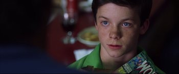 Movie still from “The Departed” (2006), directed by Martin Scorsese – A young boy sitting in front of a plate of food on a table; Close Up shot, Over the shoulder angle