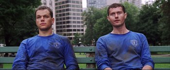 Movie still from “The Departed” (2006), directed by Martin Scorsese – Two men sitting on a park bench in front of a building; Medium shot, Low angle
