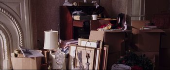 Movie still from “The Departed” (2006), directed by Martin Scorsese – A cluttered living room filled with boxes and pictures; Medium shot, High angle
