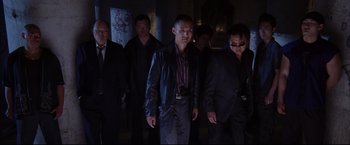 Movie still from “The Departed” (2006), directed by Martin Scorsese – A group of men standing next to each other in a dark room; Medium shot, Low angle