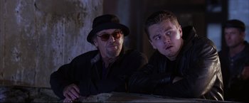 Movie still from “The Departed” (2006), directed by Martin Scorsese – A man and a man in a hat and sunglasses; Medium shot, Over the shoulder angle