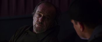 Movie still from “The Departed” (2006), directed by Martin Scorsese – An older man with a beard and mustache looking to his left; Close Up shot, Over the shoulder angle