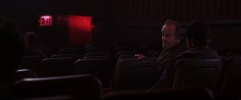 Movie still from “The Departed” (2006), directed by Martin Scorsese – A man sitting in a movie theater in the dark; Medium shot, Over the shoulder angle