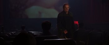 Movie still from “The Departed” (2006), directed by Martin Scorsese – A man standing in front of an audience in a movie theater; Medium shot, Over the shoulder angle