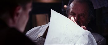Movie still from “The Departed” (2006), directed by Martin Scorsese – A man holding a piece of paper in front of his face; Close Up shot, Low angle