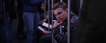 Movie still from “The Departed” (2006), directed by Martin Scorsese – A man sitting on a train with his hand under his chin; Medium shot, Low angle