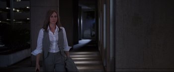 Movie still from “The Departed” (2006), directed by Martin Scorsese – A woman standing in a dark hallway holding a jacket; Medium shot, Over the shoulder angle