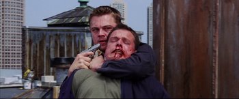 Movie still from “The Departed” (2006), directed by Martin Scorsese – A man is holding a gun while another man is holding a knife; Close Up shot, Low angle
