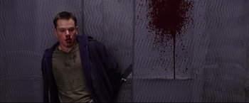 Movie still from “The Departed” (2006), directed by Martin Scorsese – A man sitting on a wall with a knife in his hand; Medium shot, High angle