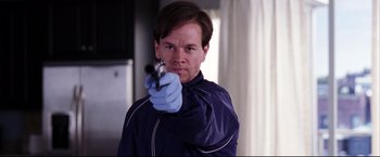 Movie still from “The Departed” (2006), directed by Martin Scorsese – A man wearing blue gloves holding a gun in his right hand; Close Up shot, Low angle