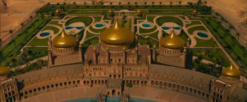 Movie still from “The Dictator” (2012), directed by Larry Charles – An aerial view of a large building with a golden dome on the top of it; Extreme Wide shot, High angle