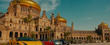 Movie still from “The Dictator” (2012), directed by Larry Charles – Cars are parked in front of a large building with golden domes; Extreme Wide shot, Low angle
