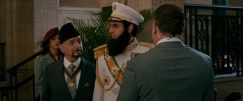 Movie still from “The Dictator” (2012), directed by Larry Charles – A man with a beard wearing a suit and hat; Medium shot, Over the shoulder angle