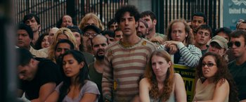 Movie still from “The Dictator” (2012), directed by Larry Charles – A man standing in a crowd of people; Medium shot, Over the shoulder angle