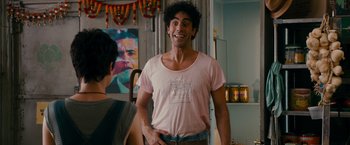 Movie still from “The Dictator” (2012), directed by Larry Charles – A man standing in front of a woman in a kitchen; Medium shot, Over the shoulder angle